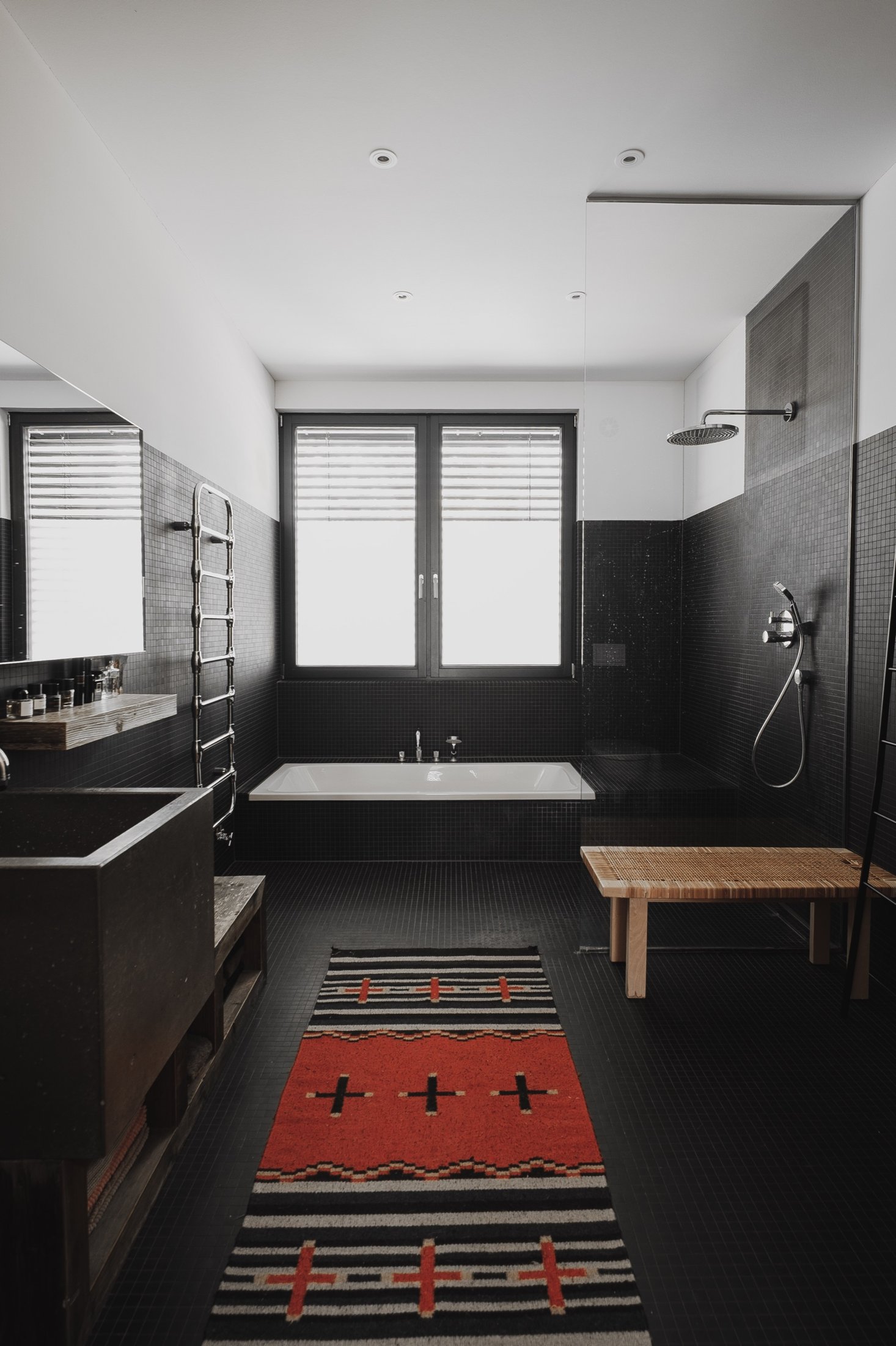 Badezimmer mit freistehender Wanne, Regendusche und rotem Kelim-Läufer, Das schwarze Haus