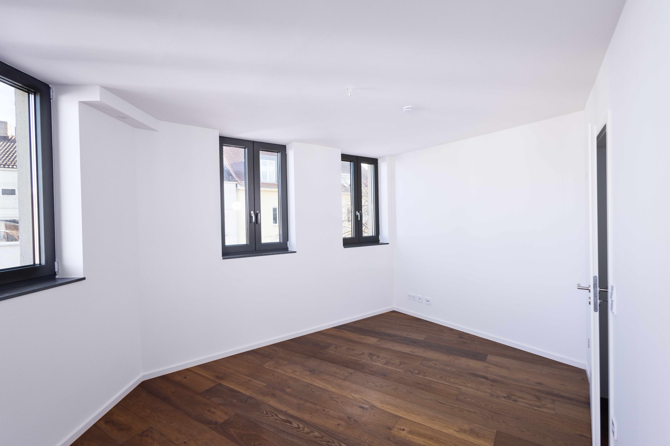 Helles Zimmer mit dunklem Eichenboden und Fenstern, Projekt Leible & Cie.