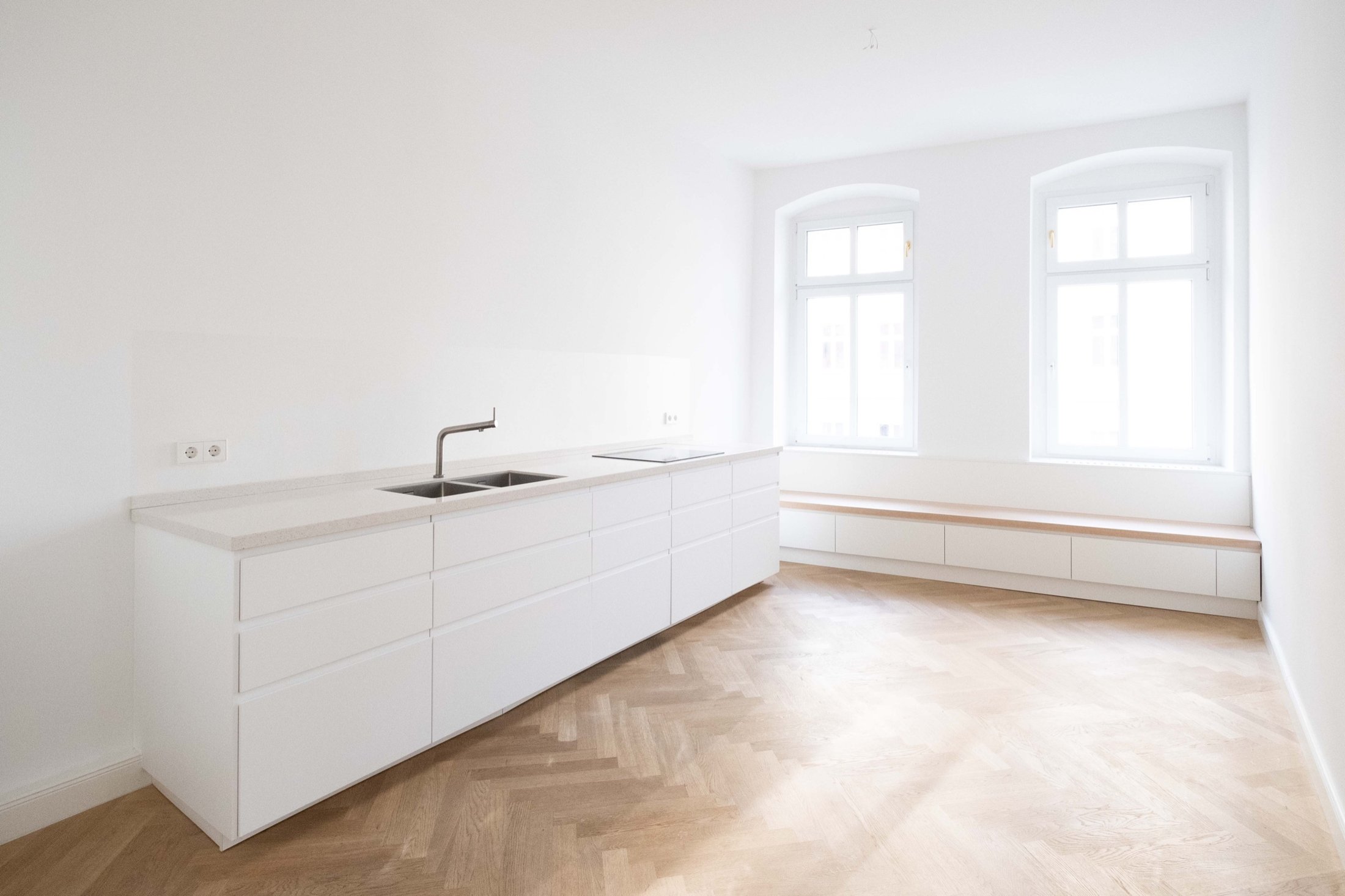 Weiße Küchenzeile mit Fischgrätparkett und Fensterbank in Altbauwohnung, Projekt Leible & Cie.