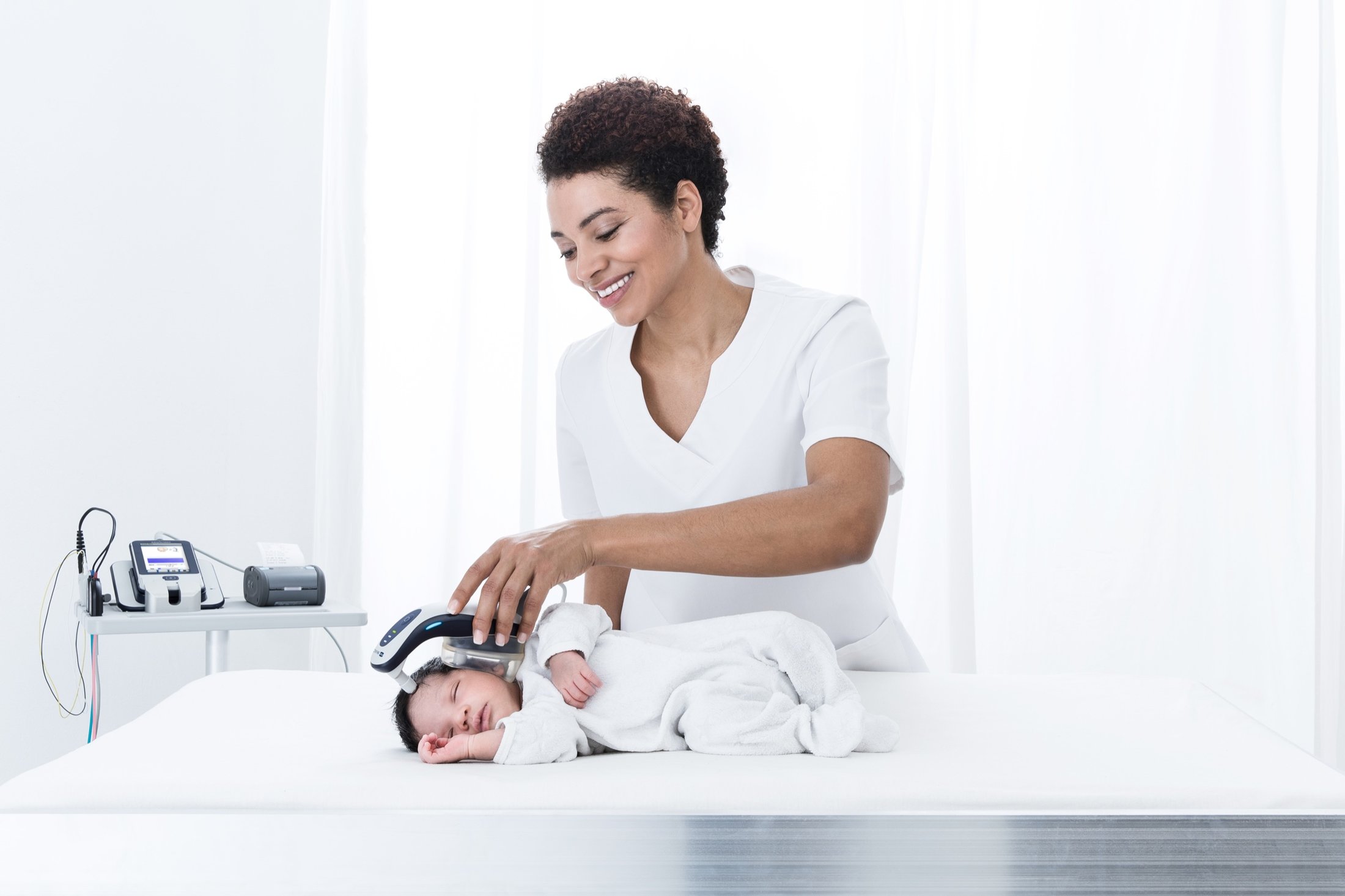 Maico Diagnostics: Hörscreening bei einem Neugeborenen, Fachkraft mit Baby auf der Liege