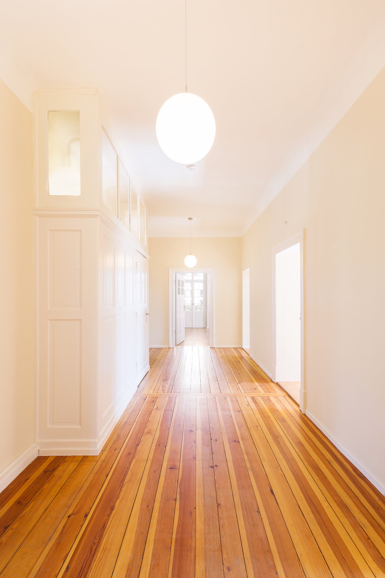 Langer Flur mit Dielenboden, Einbauschrank und Kugelleuchten, Projekt Schütze Immobilien