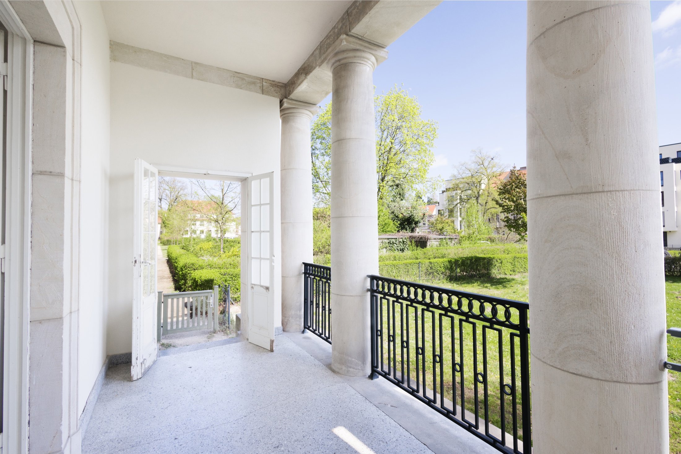 Überdachte Terrasse mit Säulen, Metallgeländer und Blick in den Garten, Projekt Schütze Immobilien