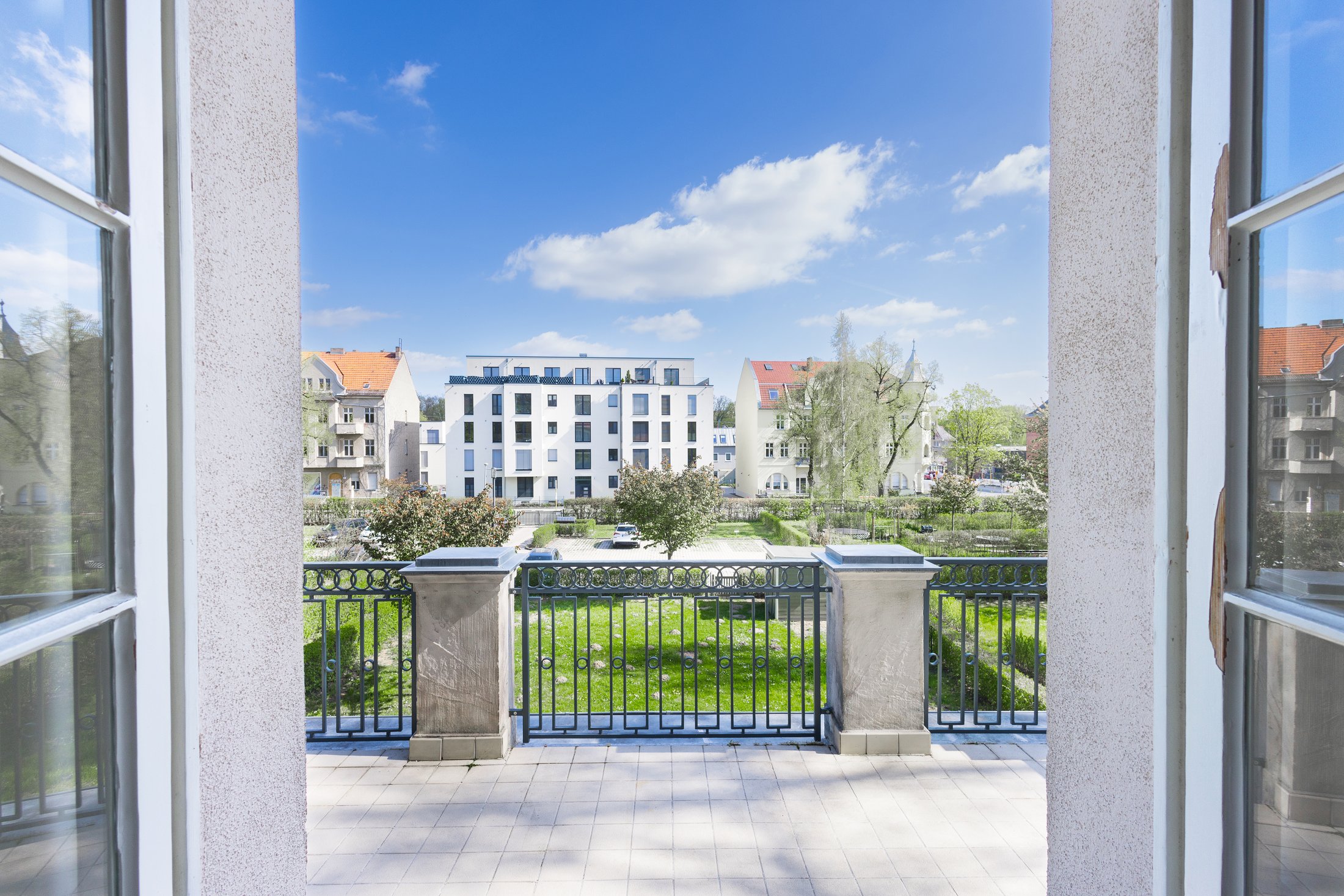 Blick durch die geöffnete Balkontür auf Garten und Nachbarbebauung, Projekt Schütze Immobilien