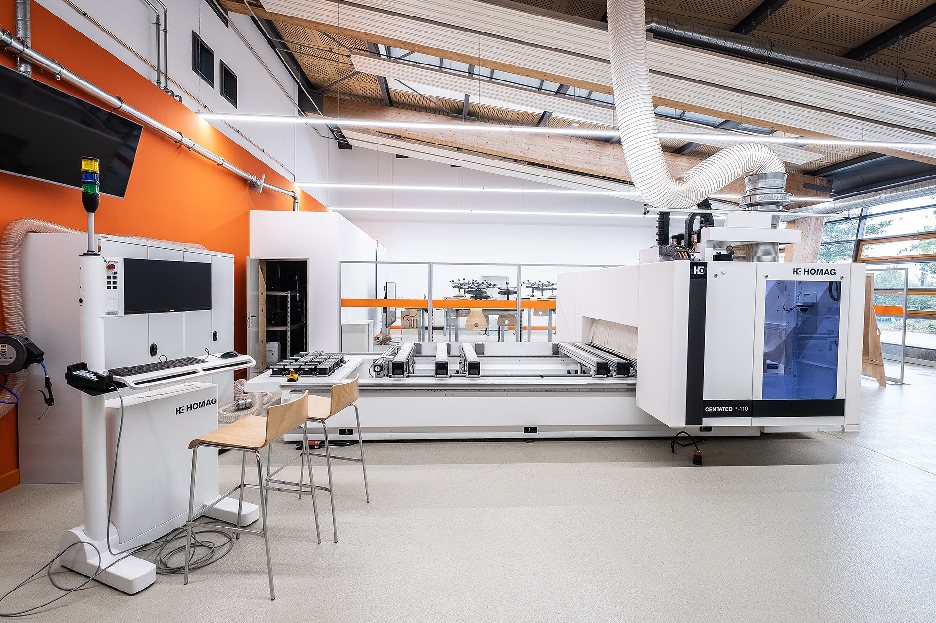CNC-Bearbeitungszentrum in heller Werkhalle vor orangefarbener Wand, Projekt DENA