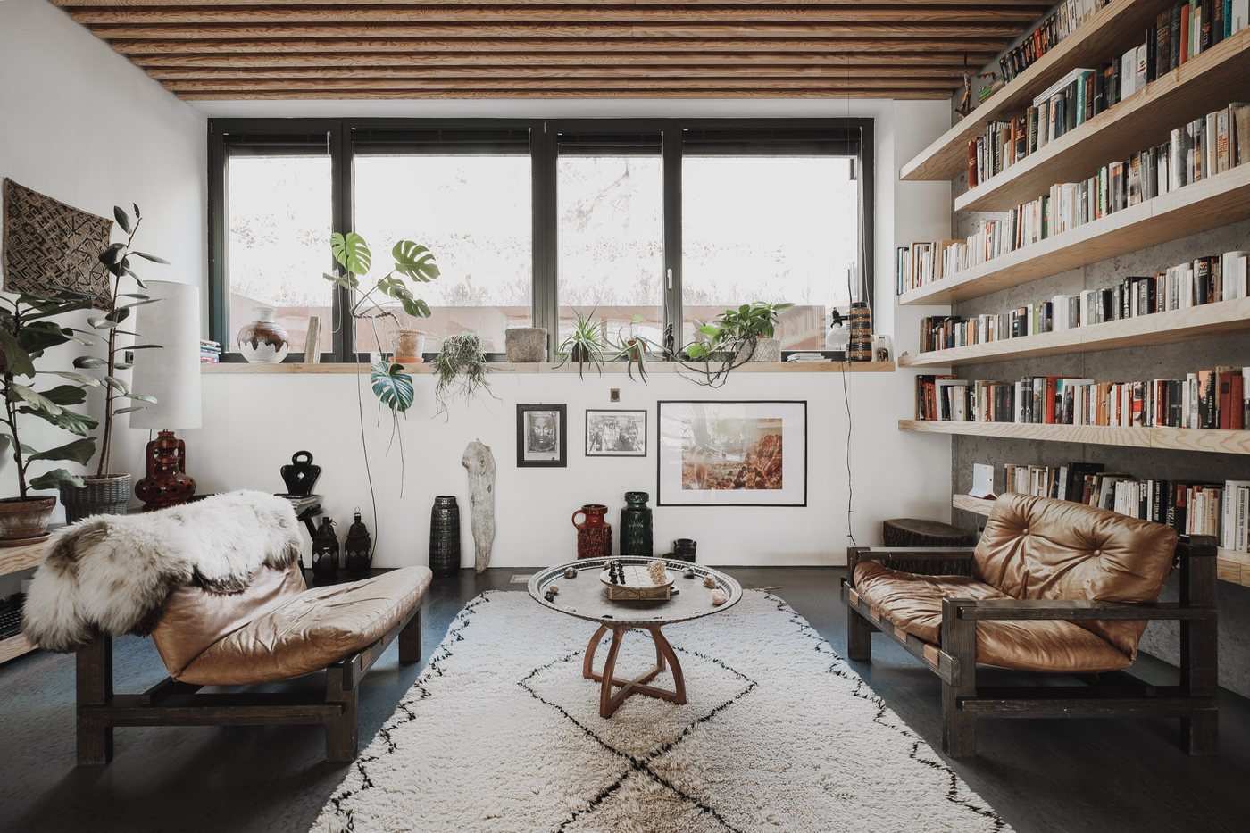 Wohnzimmer mit Bücherregalen, Ledersesseln und Fensterband, Projekt Das schwarze Haus