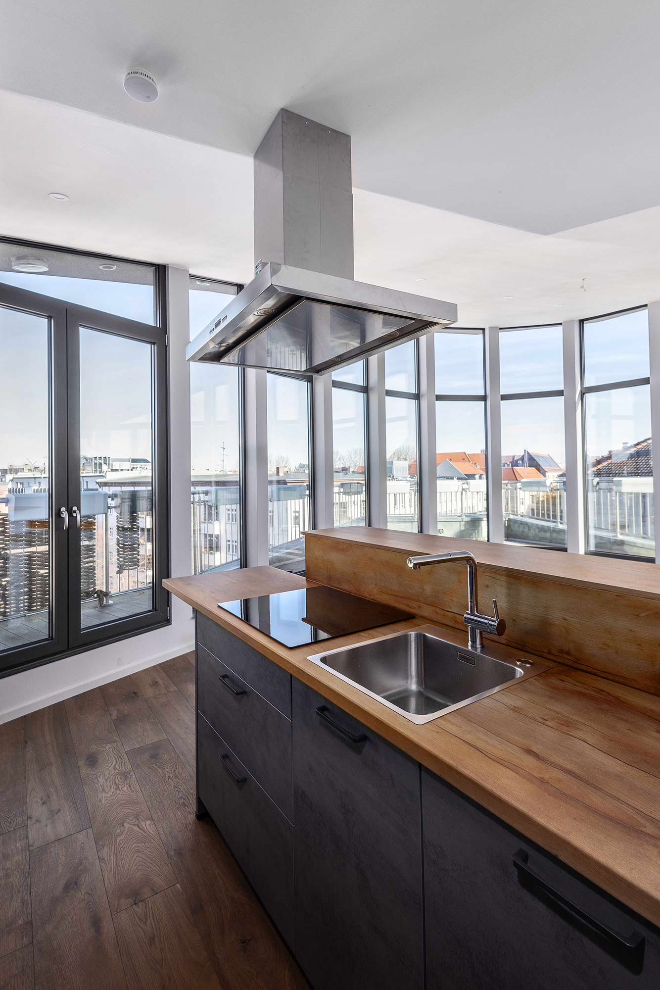 Küchenblock mit Holzarbeitsplatte, Dunstabzug und Panoramafenstern über den Dächern, Projekt Leible & Cie.